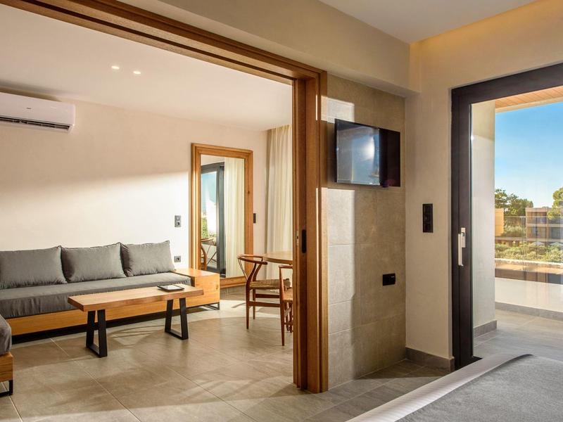 Moderne woonkamer met grijze bank, houten tafel en balkon met uitzicht.