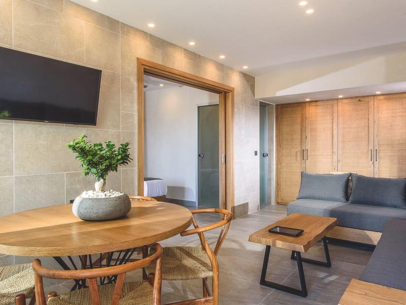 Modern ingerichte woonkamer met bank, tv, eettafel en houten details.