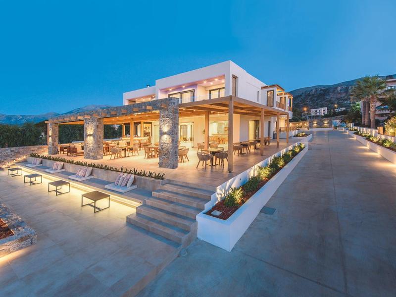 Modern hotel met verlichte buitenruimte en zitplaatsen bij schemering