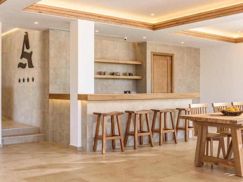 Moderne hotelinterieur met bar, houten krukken en eettafel in een lichte uitstraling.