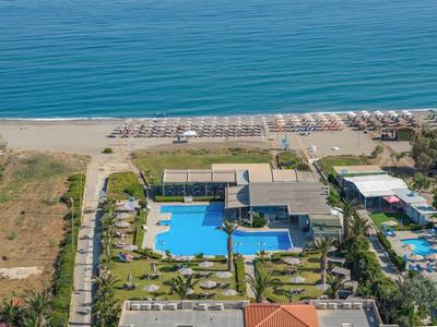 Complexe hôtelier avec piscine, transats et accès direct à la plage de sable au bord de la mer.
