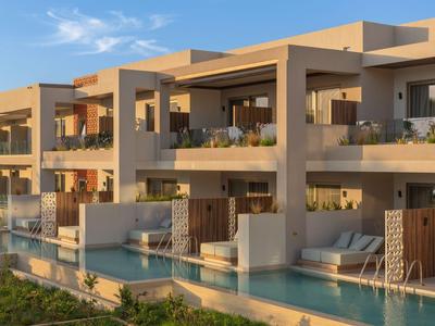 Hôtel moderne avec balcons spacieux et piscine privée au coucher du soleil.