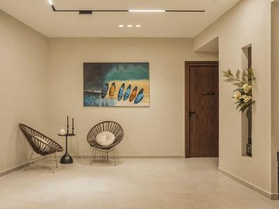 Couloir d'hôtel moderne avec deux chaises, une table et une œuvre murale colorée.