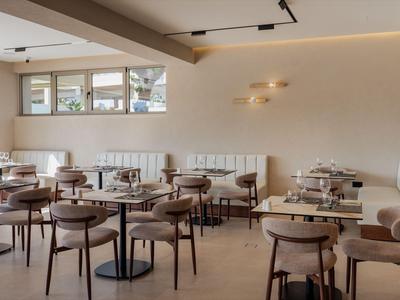 Salle à manger moderne et lumineuse avec tables et chaises rembourrées dans un hôtel.