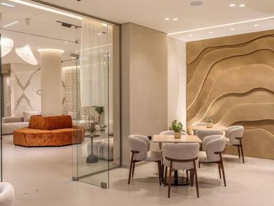 Hall d'hôtel moderne avec murs en verre, chaises confortables et décoration murale ondulée.
