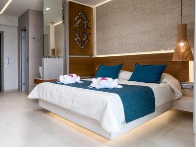 Chambre d'hôtel moderne avec lit double, coussins bleus, tapis et décoration murale.