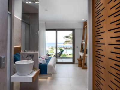Chambre d'hôtel moderne avec salle de bain spacieuse et vue sur une terrasse avec vue sur la mer.