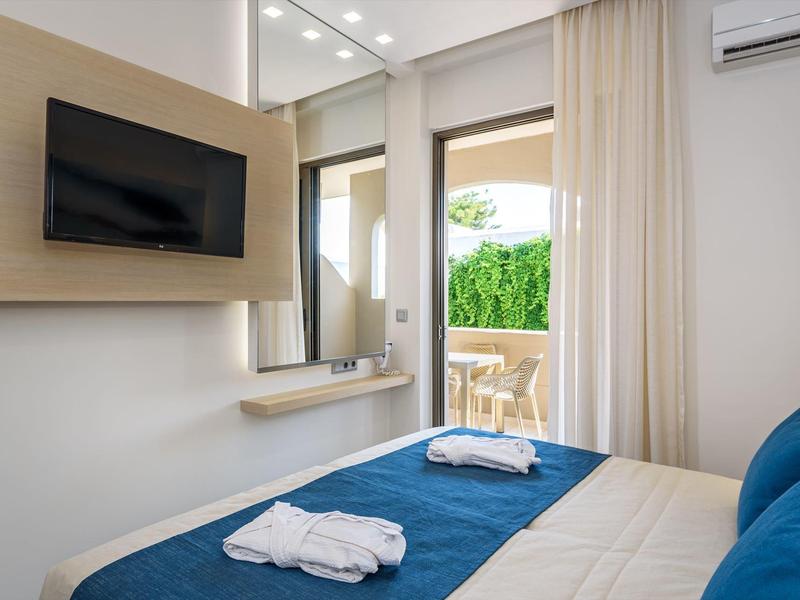 Acogedora habitación de hotel con terraza, televisión y ropa de cama limpia.