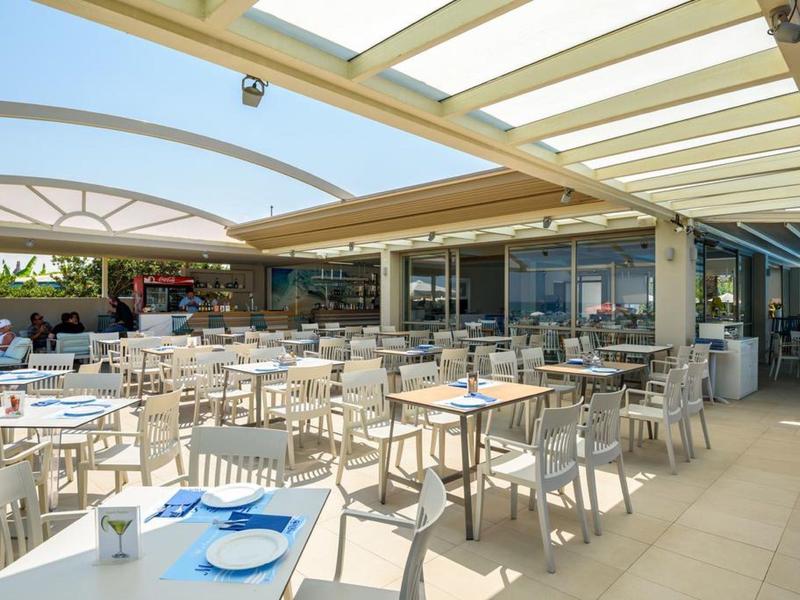 Área exterior moderna con piscina, asientos y bar en un hotel de lujo con clima soleado.