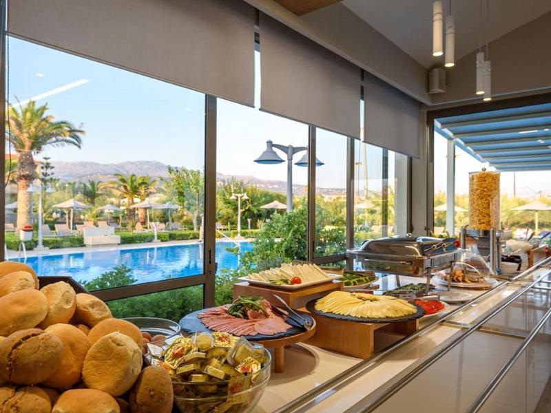 Área moderna de habitación de hotel con baño abierto, espejo redondo y vista a la cama con luz natural.
