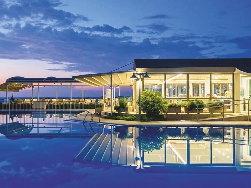 Áreas exteriores acogedoras con sillones y mesas bajo sombra cerca de la vista al mar.