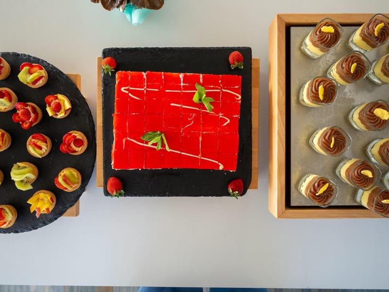 Tres postres diferentes en platos, presentados sobre una mesa blanca con decoración colorida.