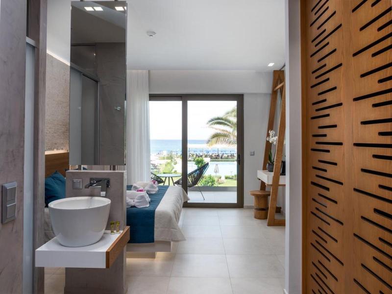 Habitación de hotel moderna con bañera, cama doble y balcón con vista al mar.