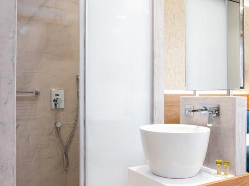 Baño moderno con ducha, pared de cristal y lavabo sobre repisa de madera.