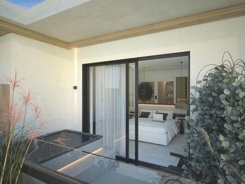 Vista de un balcón de hotel con terraza, puerta corredera de vidrio y plantas en primer plano.