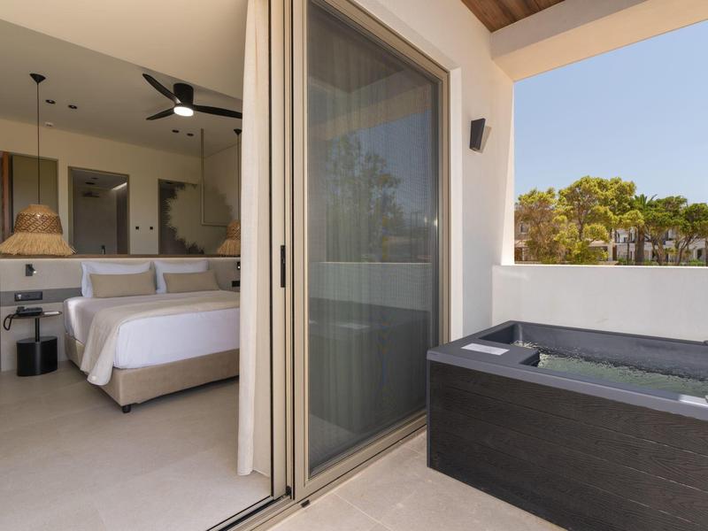 Terraza con bañera de hidromasaje y habitación de hotel moderna con cama doble y decoración minimalista.