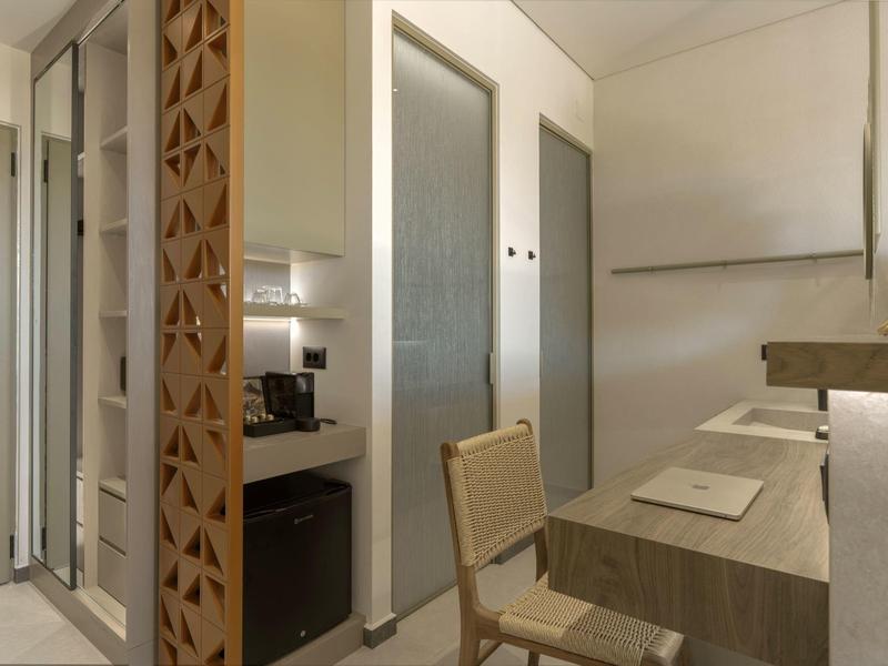 Área de trabajo moderna en hotel con silla, escritorio y cafetera en tonos neutros.