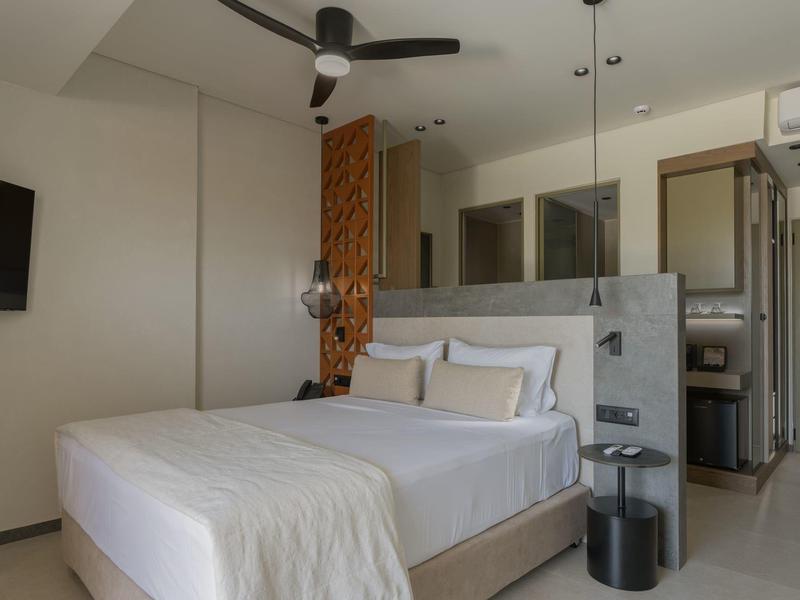 Habitación de hotel moderna con cama doble, ventilador de techo y decoración sencilla.