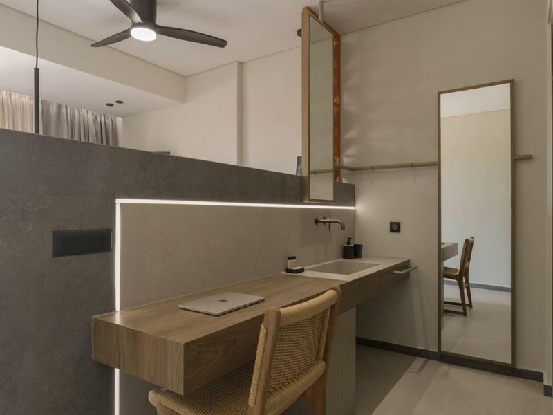 Área de trabajo moderna con mesa de madera, silla y espejo grande en colores neutros.