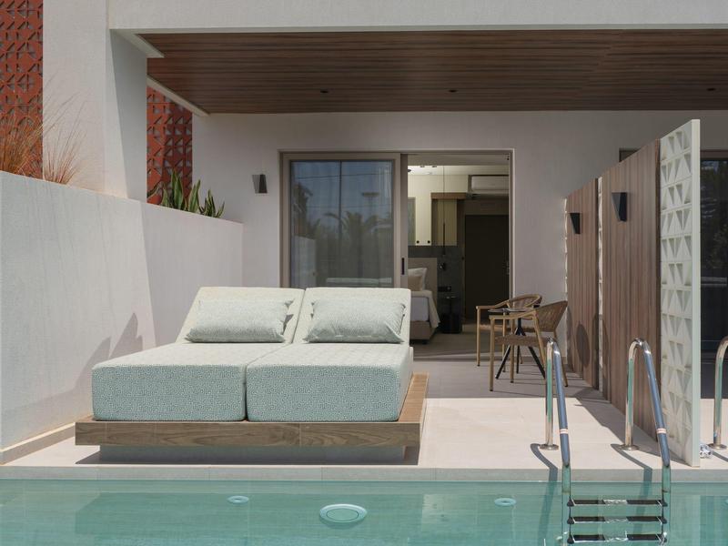 Balcón moderno de hotel con dos tumbonas, piscina y acceso abierto al interior.