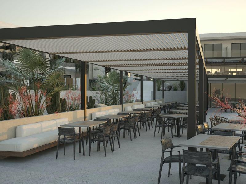 Área al aire libre moderna con mesas, sillas y salón cubierto en un hotel.