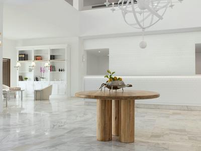 Moderner Empfangsbereich mit hellem Marmorboden und rundem Holztisch im Zentrum.