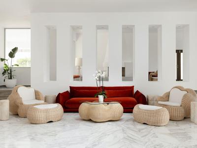 Modernes Wohnzimmer mit rotem Sofa, runden Körben und weißen Wänden mit schmalen Fenstern.