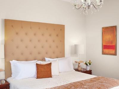 Habitación de hotel elegante con cabecero acolchado, chimenea y colores cálidos.