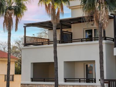 Moderner weißer Balkon eines Gebäudes mit Palmen und blauem Himmel im Hintergrund.