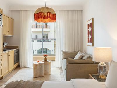 Helles Wohnzimmer mit Sofa, Couchtisch, Lampe und großem Fenster mit Blick auf Gebäude.