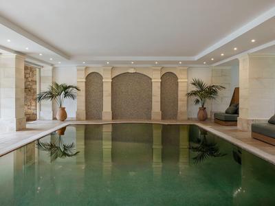 Innenpool mit Pflanzen und eleganter Wandgestaltung in einem modernen Wellnessbereich.