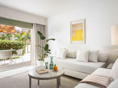 Hell eingerichtetes Wohnzimmer mit Sofa, Couchtisch und Blick auf Terrasse mit Garten