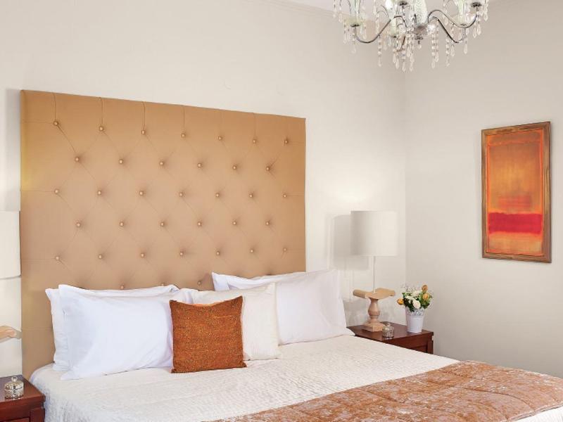 Habitación de hotel elegante con cabecero acolchado, chimenea y colores cálidos.