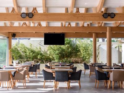 Area esterna coperta moderna dell'hotel con sedie e tavoli sotto travi di legno.