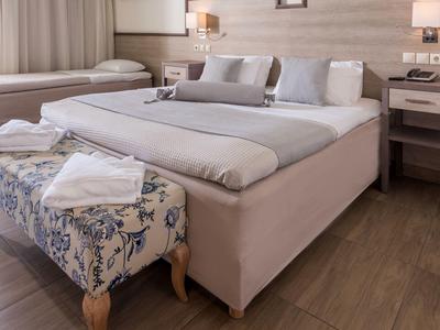 Camera d'hotel moderna con letto grande, cuscini morbidi e panca con motivo floreale ai piedi.