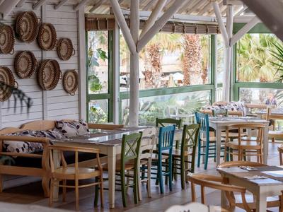 Ristorante aperto luminoso con mobili in legno e cesti decorativi al muro.