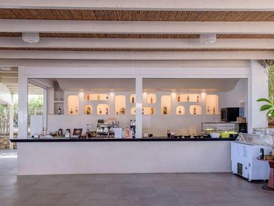 Bar dell'hotel moderna con scaffali illuminati e grande bancone in granito nero.