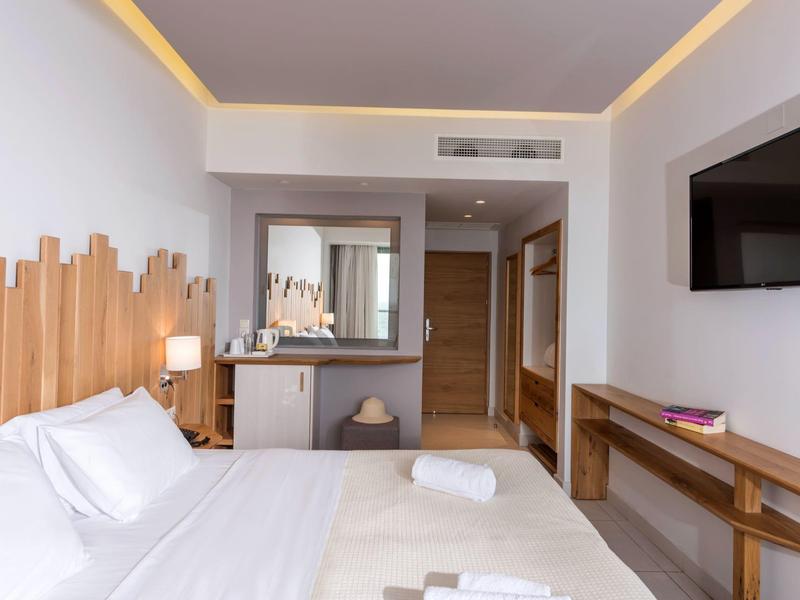 Camera d'hotel moderna con letto matrimoniale, TV a parete e arredi in legno eleganti