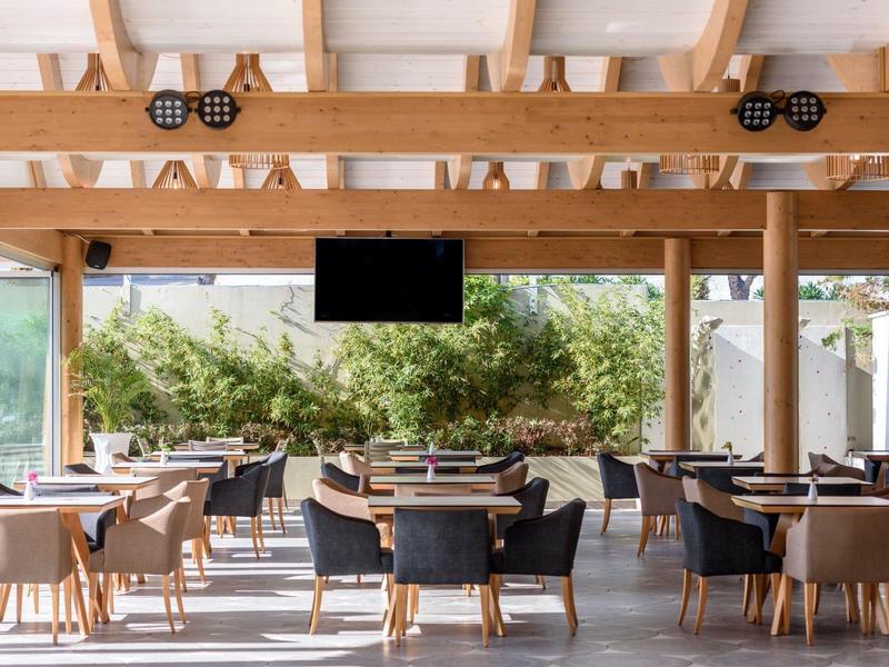 Area esterna coperta moderna dell'hotel con sedie e tavoli sotto travi di legno.