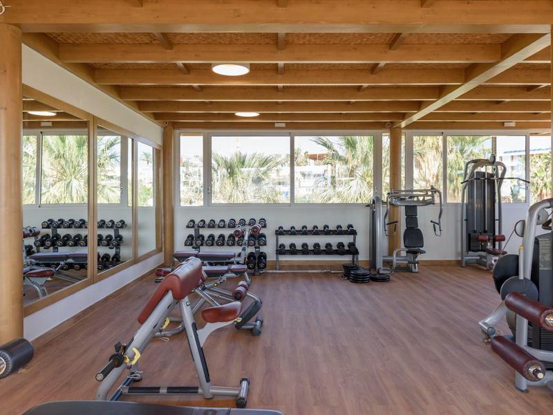 Palestra moderna con travi in legno, ampie finestre e varie attrezzature per l'allenamento.