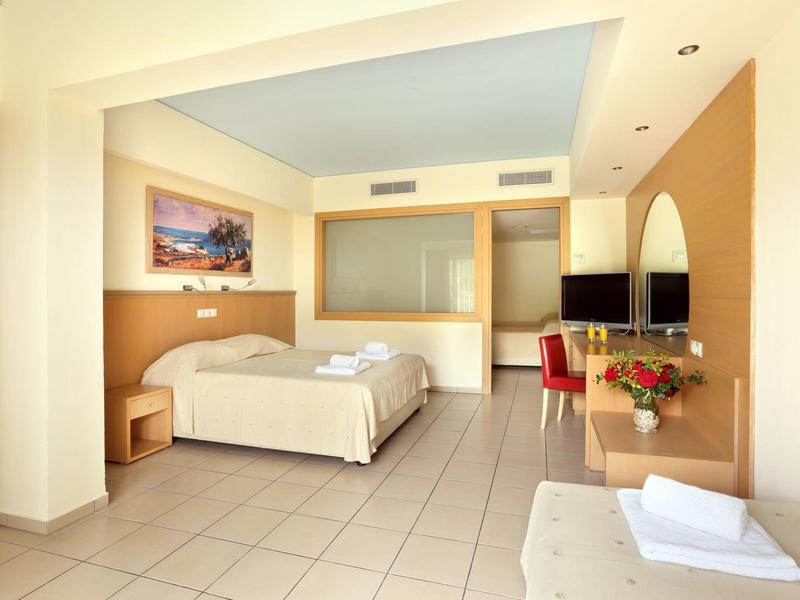 Camera d'hotel luminosa con letto matrimoniale, TV e scrivania.