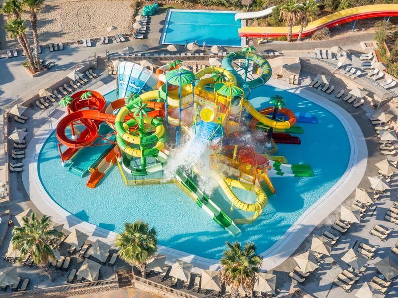 Parco acquatico colorato con scivoli e piscina per bambini in un resort.