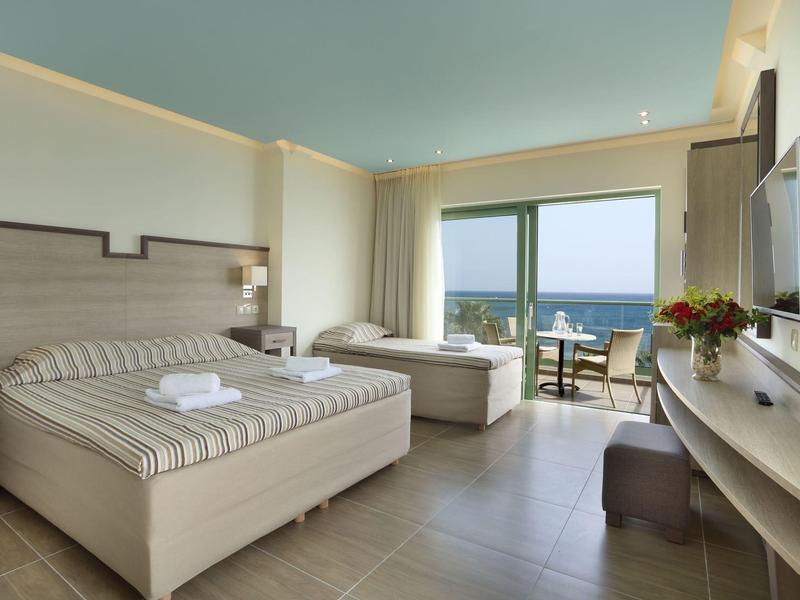 Camera d'hotel luminosa con letto matrimoniale, balcone e vista mare.