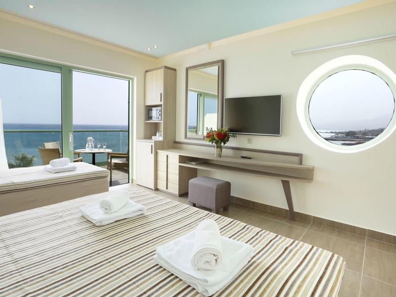 Camera d'hotel luminosa con vista mare, due letti e arredamento moderno.