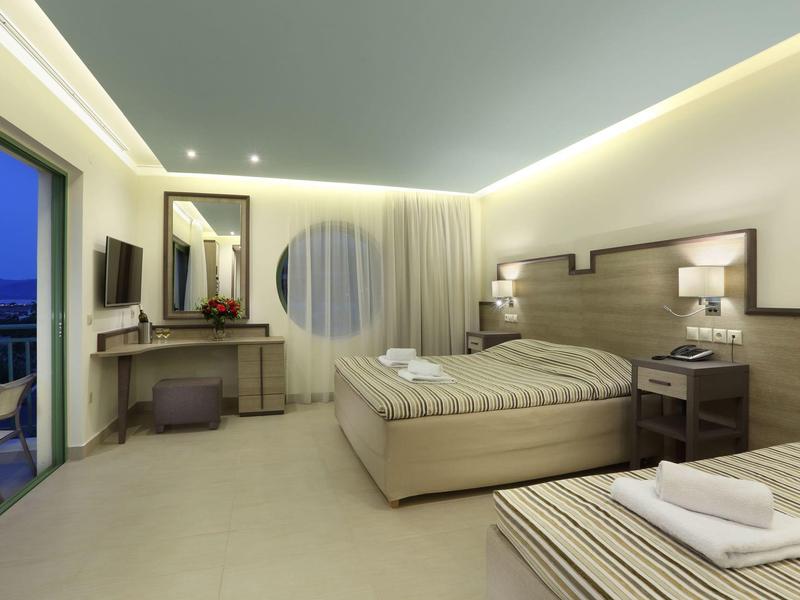 Camera d'albergo moderna con letto matrimoniale, scrivania, piccolo balcone e illuminazione indiretta.