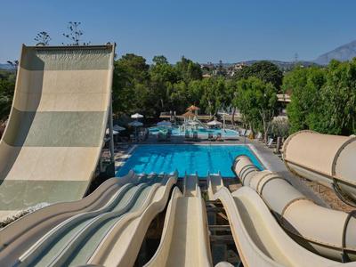 Blick auf mehrere Wasserrutschen, die zu einem großen Schwimmbecken in einer tropischen Hotelanlage führen.