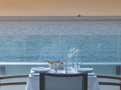 Elegantně prostřený stůl s výhledem na moře a klidnou atmosférou při západu slunce.