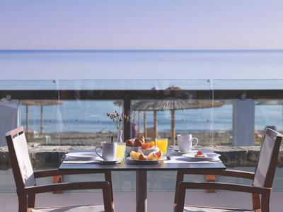 Stůl s nádobím a džusem na terase s výhledem na moře při východu slunce.