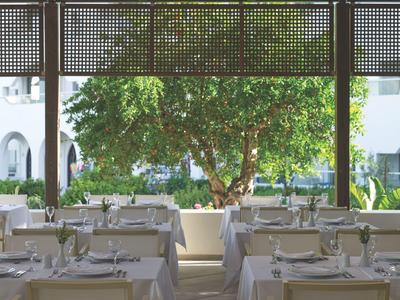 Elegantní restaurace s prostřenými stoly a výhledem na strom venku.