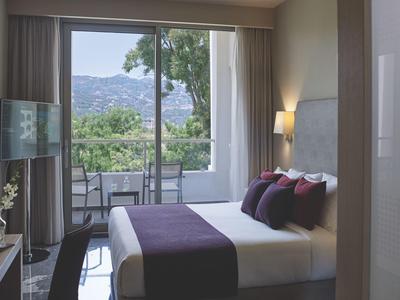 Modern hotelkamer met tweepersoonsbed en balkon met uitzicht op de bergen.